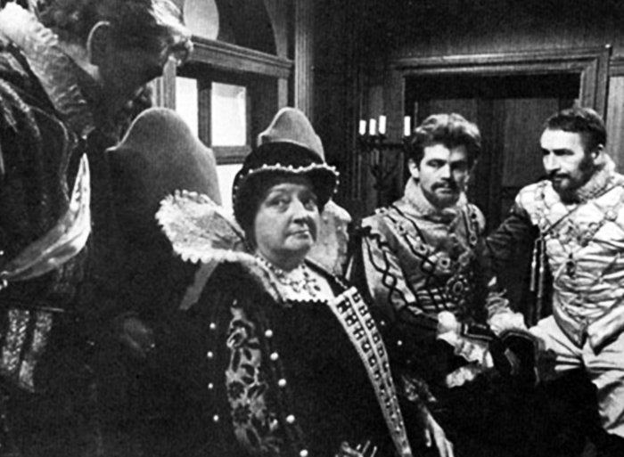 Tavannes speaks to Queenface while the King and whatshisface, the Admiral (?), consider a game of tennis.